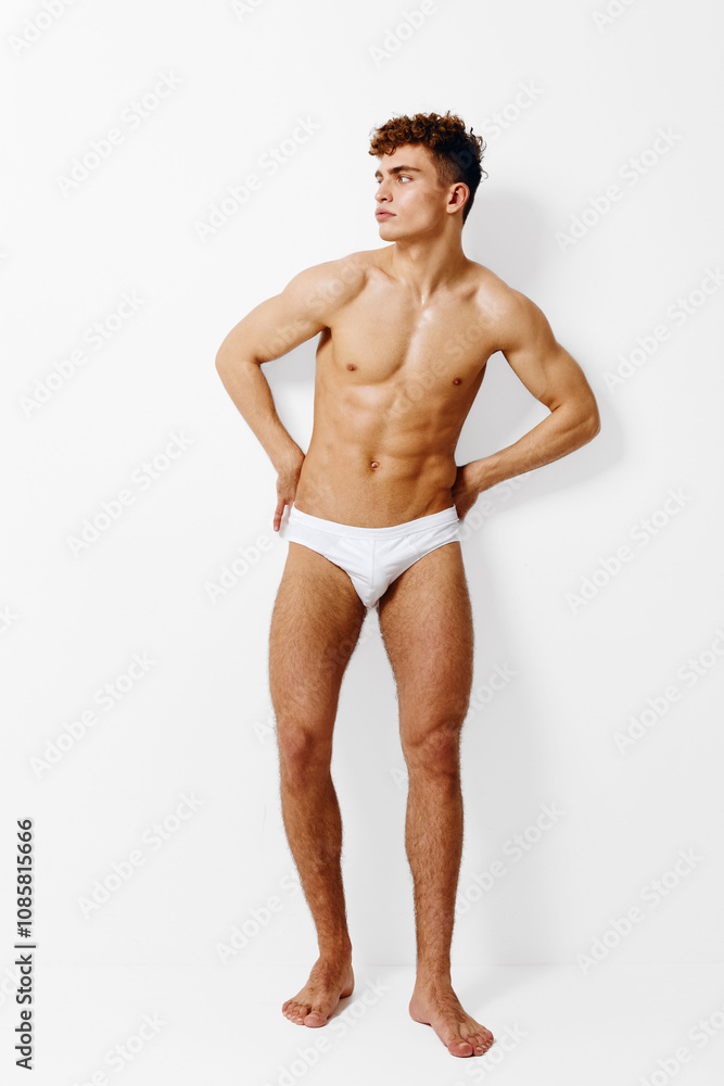 Athletic young man posing confidently in underwear against a plain white background. Fitness and self-expression concept emphasizing body positivity.