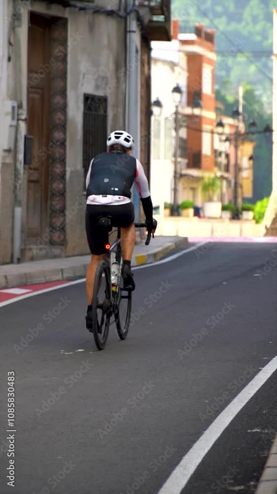 Slow motion. A cyclist racing down the village street Slow motion. A cyclist racing down the village street