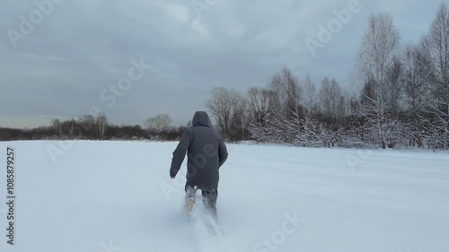 A man runs through the snow in a field.