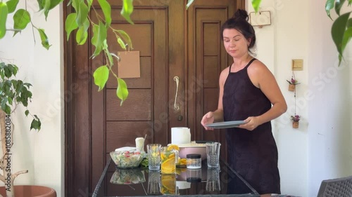 Woman cutting orange for lemonade, preparing healthy salad and serving table 