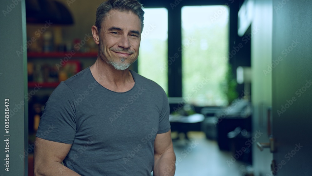 Portrait of smiling man in 50s, relaxed and confident smile, dressed in casual grey t-shirt in modern home interior. Happy mid adult, middle aged male looking at camera. Portrait of smiling man in 50s, relaxed and confident smile, dressed in casual grey t-shirt in modern home interior. Happy mid adult, middle aged male looking at camera.