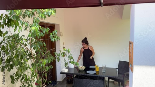 Woman cutting orange for lemonade, preparing healthy salad and serving table 