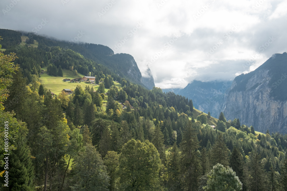Overcast above mountain slopes with pine trees and isolated houses near Wengen, Switzerland Overcast above mountain slopes with pine trees and isolated houses near Wengen, Switzerland