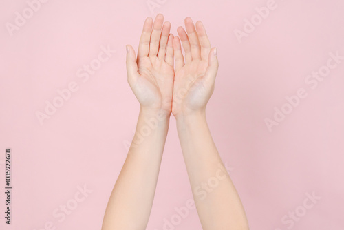 Manicured nails, beautiful woman hands forming an elegant shape on pink background