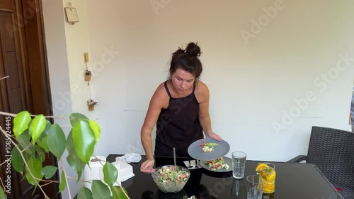 Woman cutting orange for lemonade, preparing healthy salad and serving table 