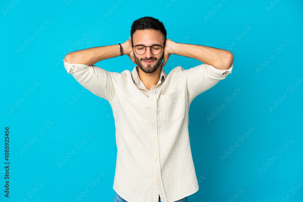 Young caucasian man isolated on blue background frustrated and covering ears Young caucasian man isolated on blue background frustrated and covering ears