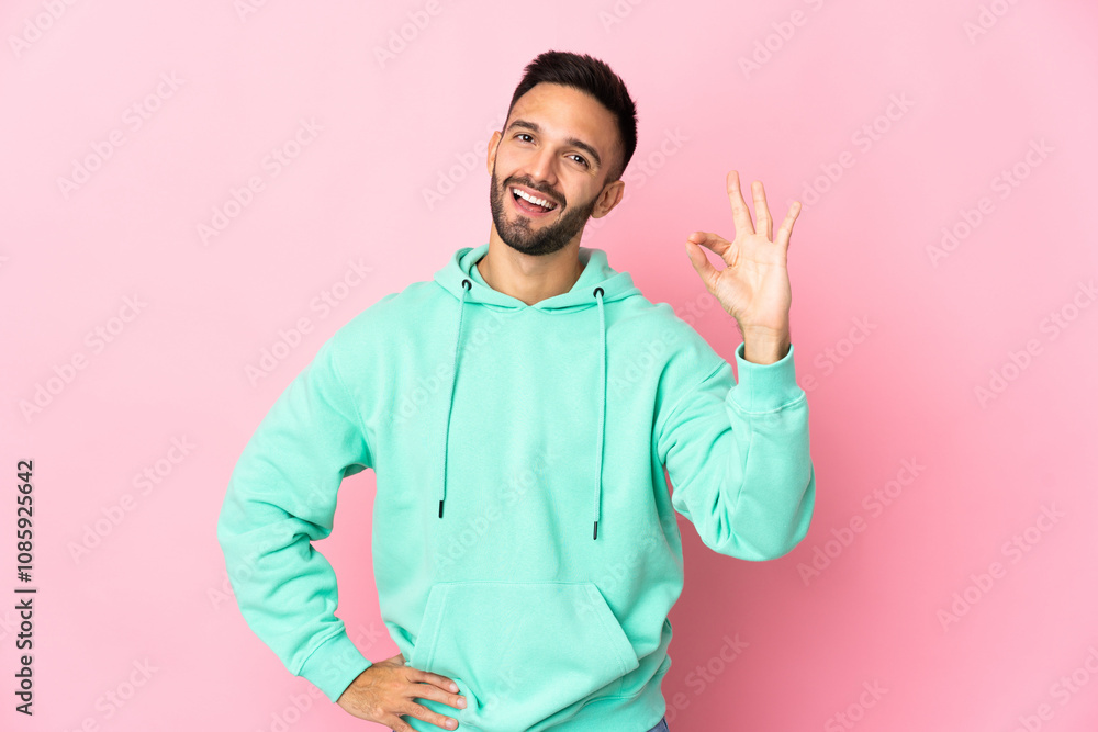 Young caucasian man isolated on pink background showing ok sign with fingers Young caucasian man isolated on pink background showing ok sign with fingers