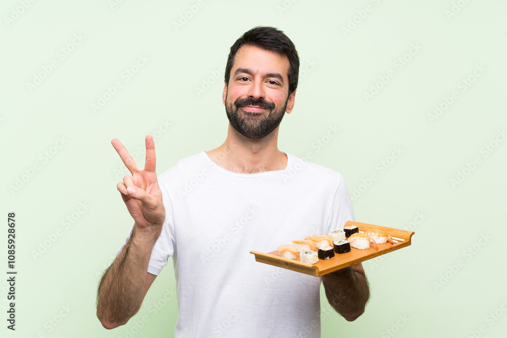 custom made wallpaper toronto digitalYoung handsome man with sushi over isolated green wall showing victory sign with both hands
