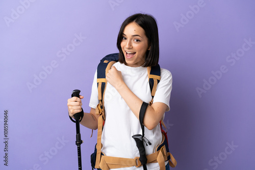 Young caucasian woman with backpack and trekking poles isolated on blue background celebrating a victory