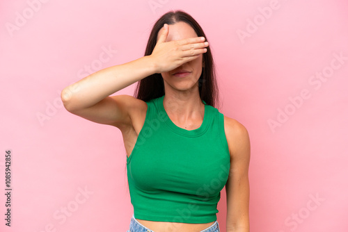 Young caucasian woman isolated on pink background covering eyes by hands. Do not want to see something