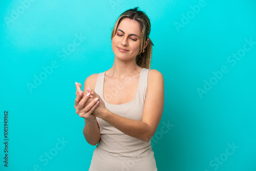 Young caucasian woman isolated on blue background suffering from pain in hands