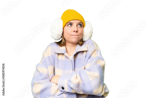 Young blonde woman wearing winter muffs over isolated chroma key background making doubts gesture while lifting the shoulders photo