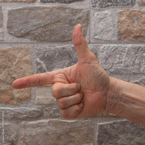 Hand forming the number two sign against a textured stone wall background photo