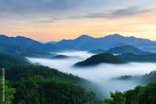 The mountains are covered in fog and the sky is a beautiful orange color. The scene is peaceful and serene, with the mist adding a sense of mystery to the landscape