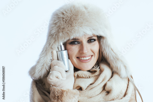 happy modern woman in winter coat and fur hat on white