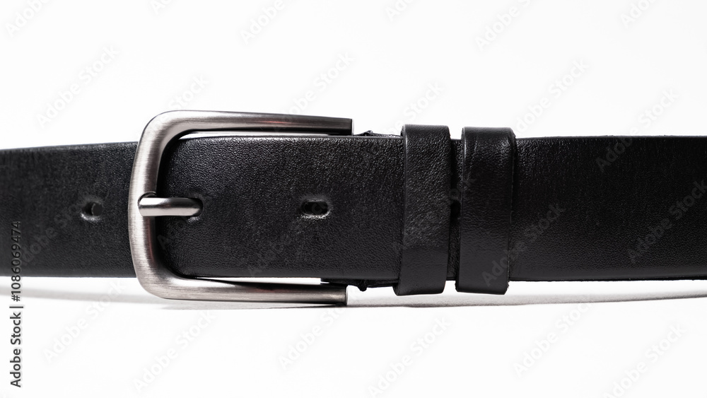 Black Classical leather Belt isolated on white background close-up. Fastened fashionable unisex accessory with dark chrome matted metal buckle. Man lux strap. Haberdashery goods. Minimalistic style Black Classical leather Belt isolated on white background close-up. Fastened fashionable unisex accessory with dark chrome matted metal buckle. Man lux strap. Haberdashery goods. Minimalistic style
