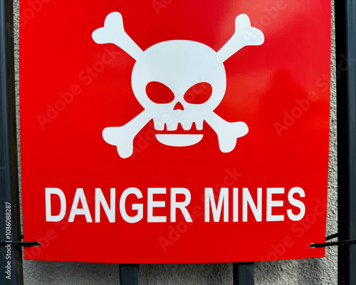 A red plate with a white skull and crossbones and the inscription “Danger mines”.
