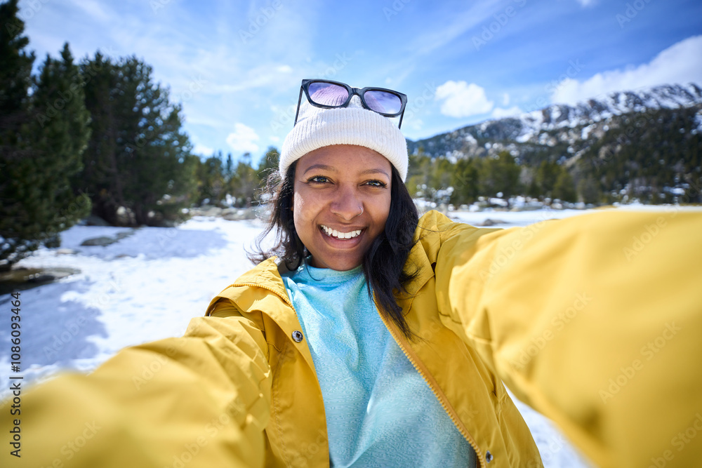 POV of African American young woman taking selfie with two hands with mobile in snowy mountains. Generation Z Latin beautiful female in yellow looking smiling at camera sunny day of winter holidays POV of African American young woman taking selfie with two hands with mobile in snowy mountains. Generation Z Latin beautiful female in yellow looking smiling at camera sunny day of winter holidays