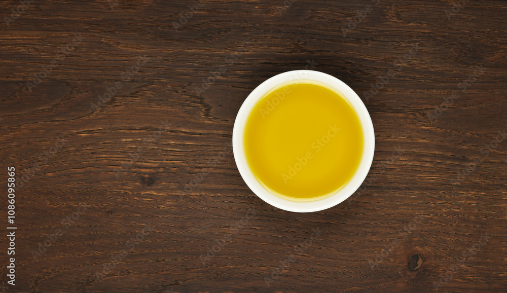 Small white bowl with fresh aromatic olive oil on dark wooden table Small white bowl with fresh aromatic olive oil on dark wooden table