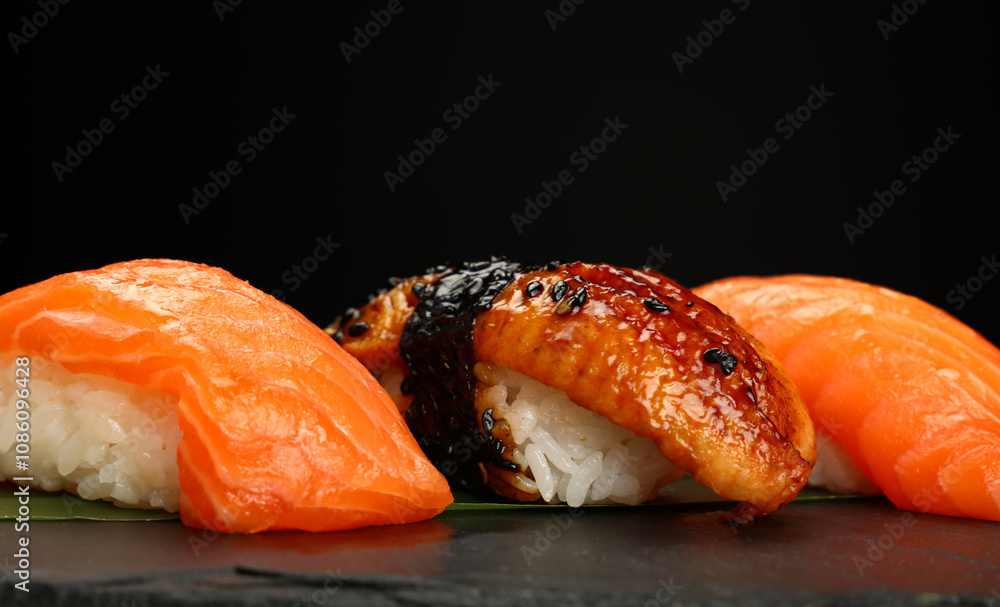 Delicious sushi pieces with salmon, eel and rice on black background Delicious sushi pieces with salmon, eel and rice on black background