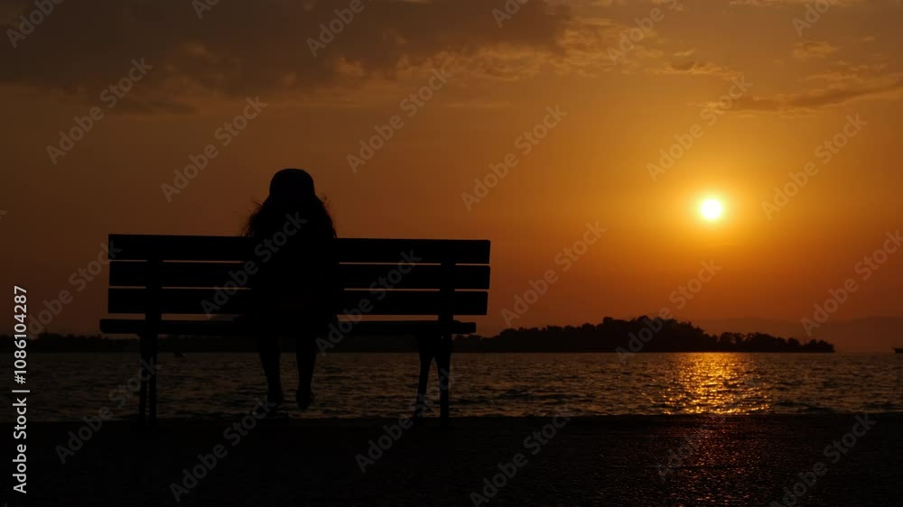 Silhouette of child on bench at coastline. A view of child silhouette sitting on bench and enjoy the sunset sea coastline. Silhouette of child on bench at coastline. A view of child silhouette sitting on bench and enjoy the sunset sea coastline.