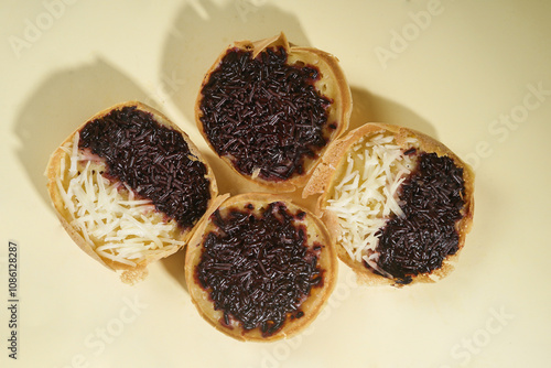 Martabak mini or terang bulan mini is Indonesian popular street food, made from flour, egg, yeast, topped with cheese or chocolate. Mini sweet martabak isolated on yellow background. photo