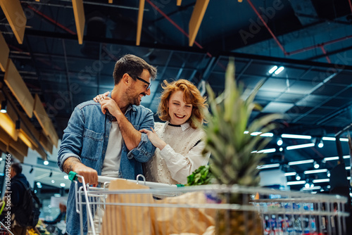 Fotografi Happy couple pushing shopping cart in supermarket