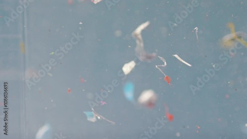Colorful microplastics swirl in water in a close-up view, emphasizing contamination and the ecological issue of waste pollution.