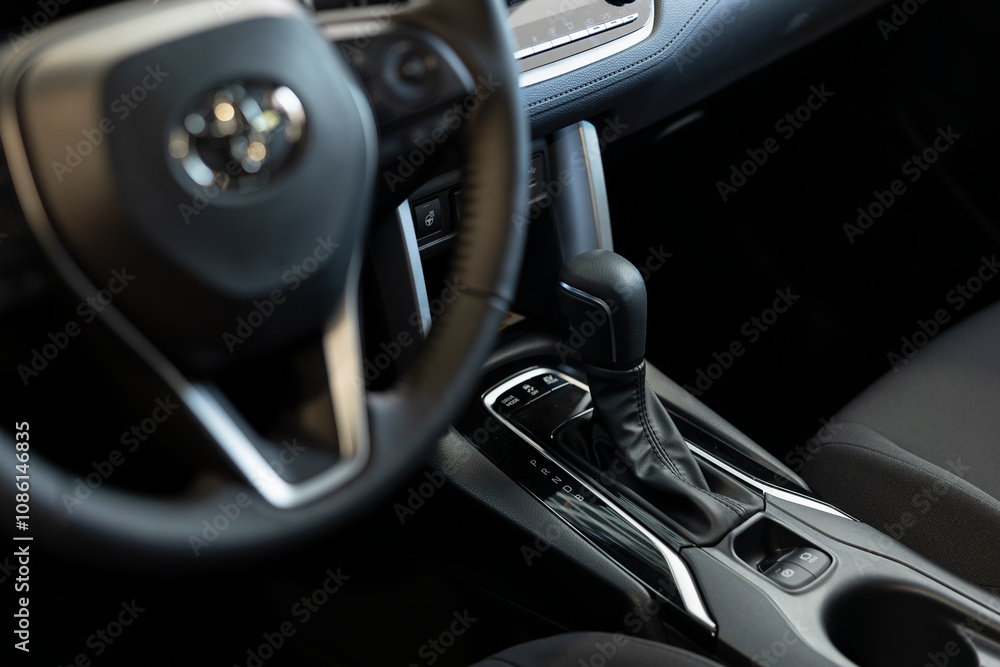 Close up of car interior steering wheel and gearbox gear shift, transmission control panel and buttons activating different vehicle functions. Focus on vehicle automatic gearbox control buttons Close up of car interior steering wheel and gearbox gear shift, transmission control panel and buttons activating different vehicle functions. Focus on vehicle automatic gearbox control buttons