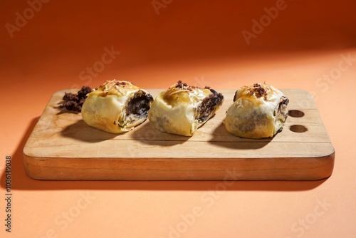 Banana bolen is made from banana and pastry skin and has chocolate and cheese filling. Served in wooden plate. Selective focus image. photo