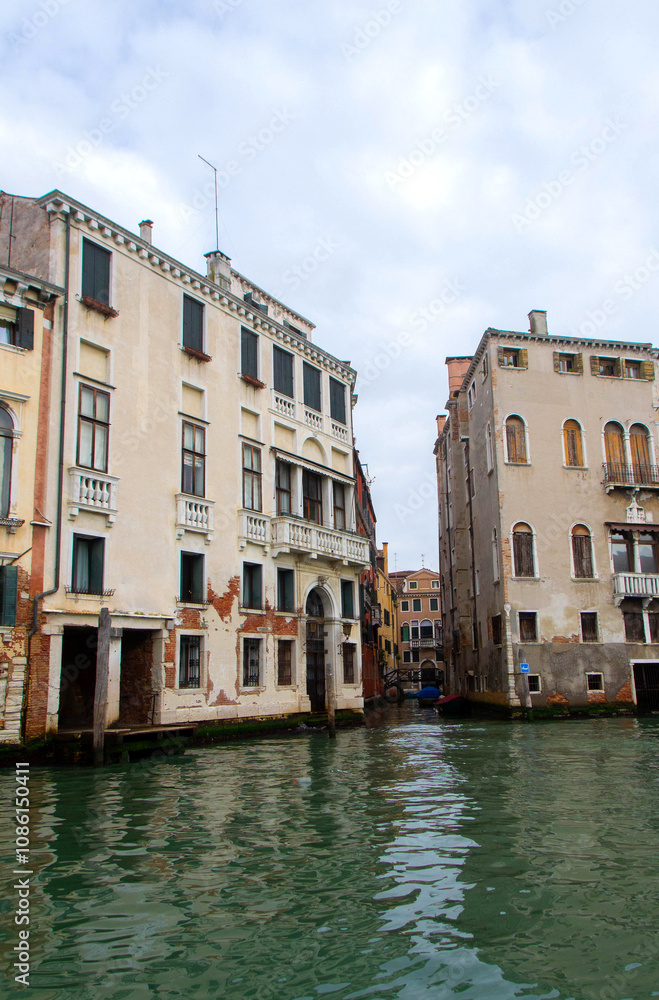 A view of historic Venetian buildings along the Grand Canal, showcasing classic Italian architecture. The iconic canal waters reflect the facades, with boats and gondolas adding to the charm of Venice A view of historic Venetian buildings along the Grand Canal, showcasing classic Italian architecture. The iconic canal waters reflect the facades, with boats and gondolas adding to the charm of Venice