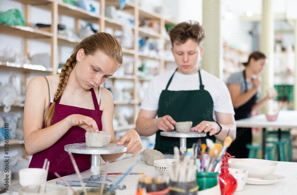 Students teenage girl and teenage boy sculpt ceramic product from raw clay in workshop Students teenage girl and teenage boy sculpt ceramic product from raw clay in workshop