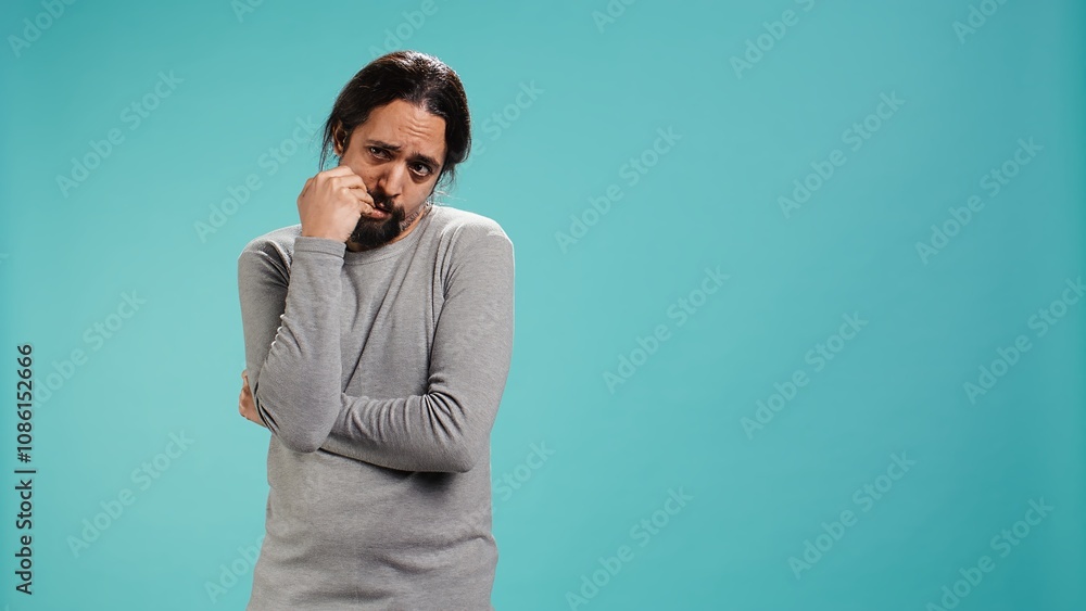 Distraught man biting nails, being afraid of receiving troubling bad news, studio background. Anxious person suffering from mental health problems, having negative emotions, camera B Distraught man biting nails, being afraid of receiving troubling bad news, studio background. Anxious person suffering from mental health problems, having negative emotions, camera B