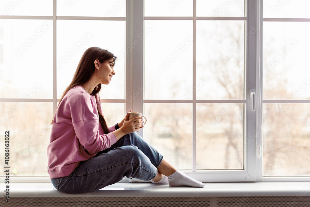Time For Yourself. Profile side view of calm casual lady sitting on white modern windowsill at home, looking through the glass window, holding cup and drinking hot coffee, thinking. Free copy space Time For Yourself. Profile side view of calm casual lady sitting on white modern windowsill at home, looking through the glass window, holding cup and drinking hot coffee, thinking. Free copy space