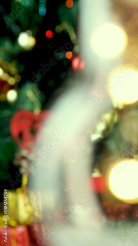 Blurred video for background image. Moving light bulb in front of a decorated Christmas tree. Vertical video, details. Scene background.