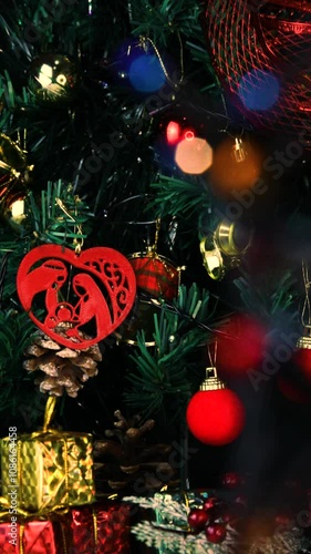 Blurred lights in motion in front of a decorated Christmas tree. Vertical video, details. Scene background.