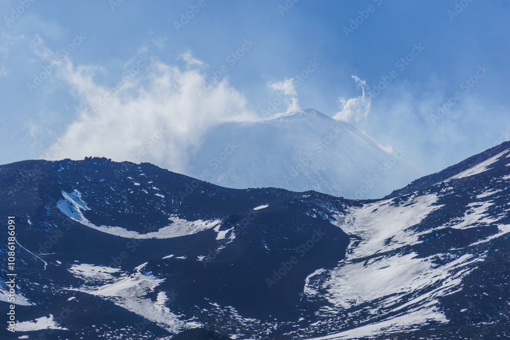 Beautiful detail view at the peak of Mount Etna Volcano covered in snow with clouds surrounding the summit, Catania, Sicily, Italy Beautiful detail view at the peak of Mount Etna Volcano covered in snow with clouds surrounding the summit, Catania, Sicily, Italy