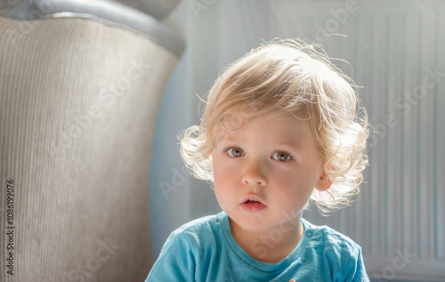 Sweet little child boy portrait sitting on the floor at home, beautiful morning light