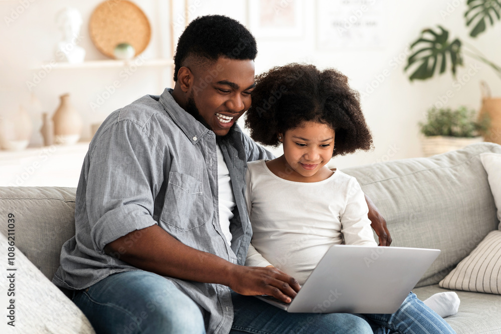 Happy African Father And His Little Daughter Using Laptop At Home Together, Resting On Sofa, Watching Movies Online Or Browsing Internet Happy African Father And His Little Daughter Using Laptop At Home Together, Resting On Sofa, Watching Movies Online Or Browsing Internet