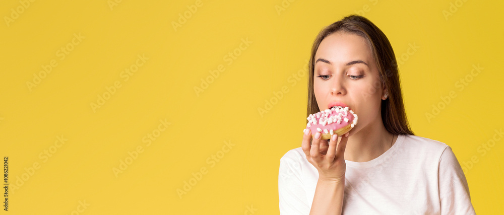 Portrait of hungry young lady eating donut isolated over yellow background with copy space Portrait of hungry young lady eating donut isolated over yellow background with copy space