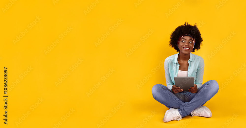 Happy Black Woman Using Digital Tablet Looking Aside At Free Space Sitting On Floor On Pink Studio Background. Bushy African Lady Posing With Computer. Gadget Lifestyle And Online Technology Concept Happy Black Woman Using Digital Tablet Looking Aside At Free Space Sitting On Floor On Pink Studio Background. Bushy African Lady Posing With Computer. Gadget Lifestyle And Online Technology Concept