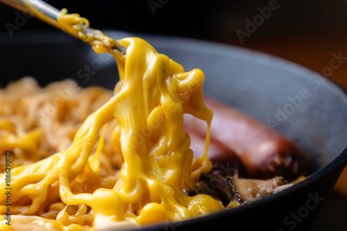 lifting cheesy hot ramen noodles with chopsticks photo