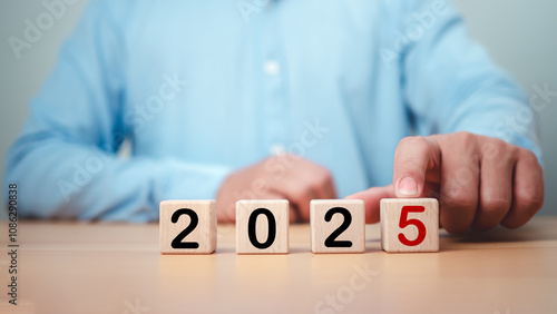 Businessman selected cube from 2025 on wooden table, Planning 2025 trends new year symbol, Concept words 2025 start on beautiful wooden blocks, Business 2025 target new year concept. Copy space.