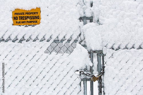 Fence covered in snow with no trespassing sign photo