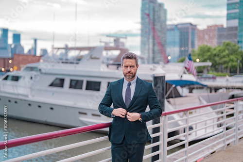 Businessman posing outdoor in New York City. Business American success. American business dream. American businessman in suits near office building and yacht. Business in USA. photo