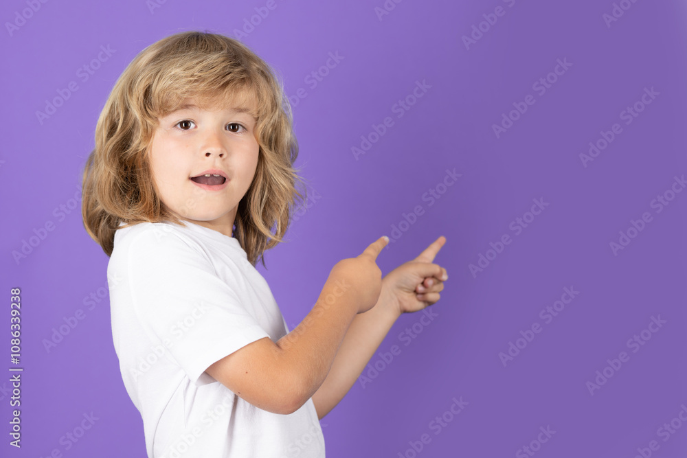 Funny child pointing finger on isolated studio background. Kid pointing to copyspace, showing promo offers, points away. Advertisement promo product concept. Funny child pointing finger on isolated studio background. Kid pointing to copyspace, showing promo offers, points away. Advertisement promo product concept.