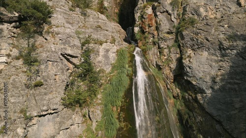 Grunas waterfall in Albania cascades down rugged rock cliffs surrounded by lush green vegetation photo