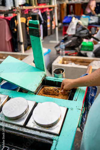 A seller adds peanut topping to Es Goyang. Es Goyang is a traditional ice cream made from coconut milk, granulated sugar and hunkwe flour which is sold using a wooden cart. photo