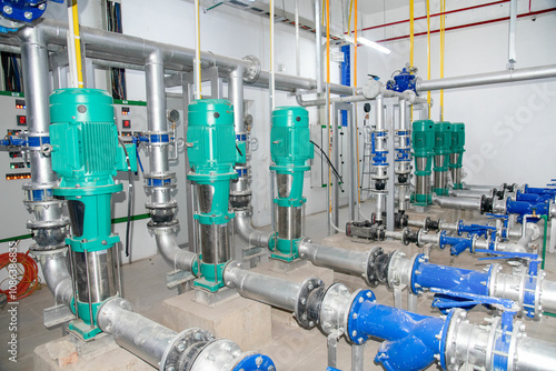 Industrial interior of water pump, valves, pressure gauges, motors inside engine room. Valve and pumps in an industrial room. Urban modern powerful pipelines and pumps, automatic control systems