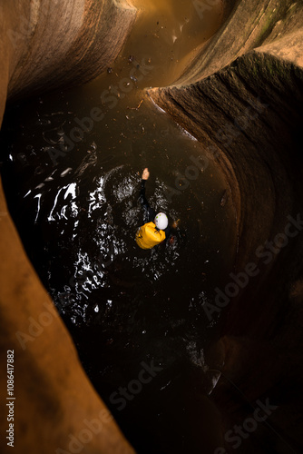 Man canyoneering and swimming thru a canyon with a yellow backpack